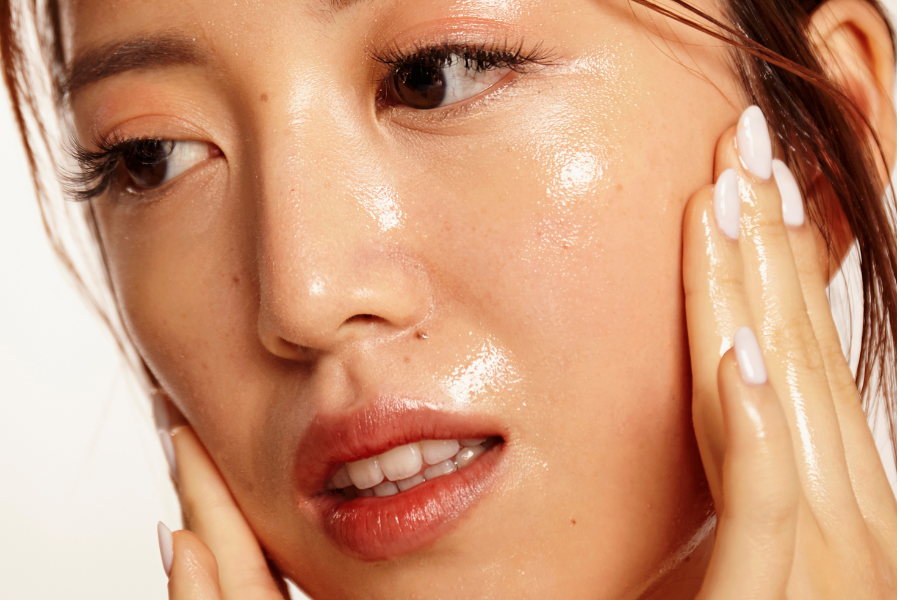 Close-up of dewy Korean glass skin while applying hydrating skincare cream