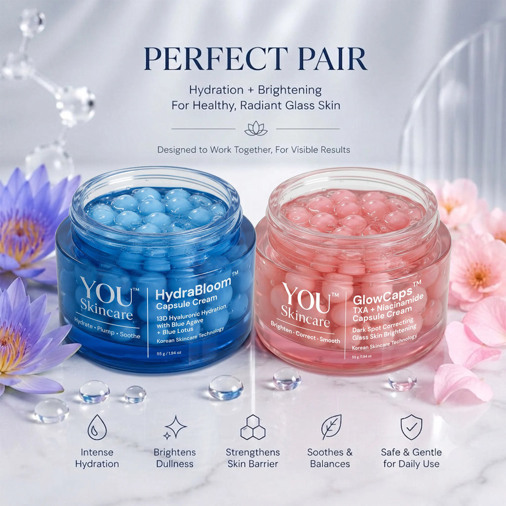 Two open cosmetic jars on a glossy white surface with decorative flowers and water droplets: a blue jar labeled YOU Skincare HydraBloom Capsule Cream and a pink jar labeled YOU Skincare GlowCaps 32+ Micronized Capsule Cream. Text above reads 'PERFECT PAIR' and below lists benefits.