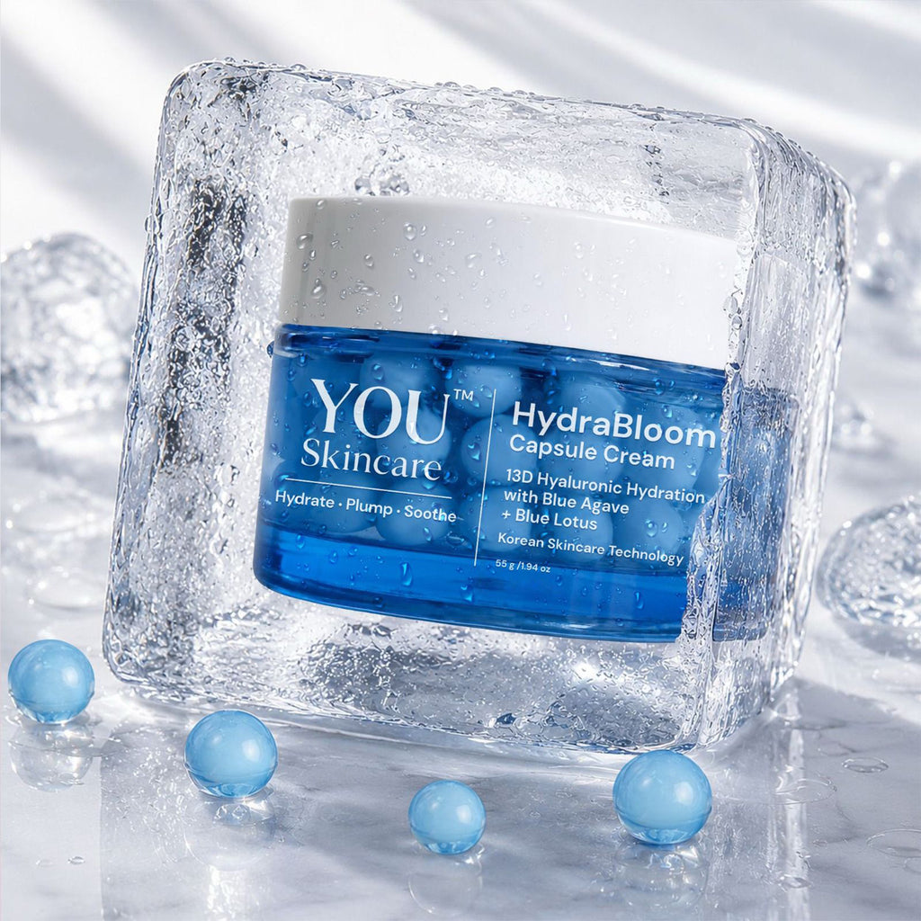 YOU Skincare HydraBloom Capsule Cream in a blue jar with a white lid, presented inside a clear ice cube with scattered blue gel beads on a reflective white surface.
